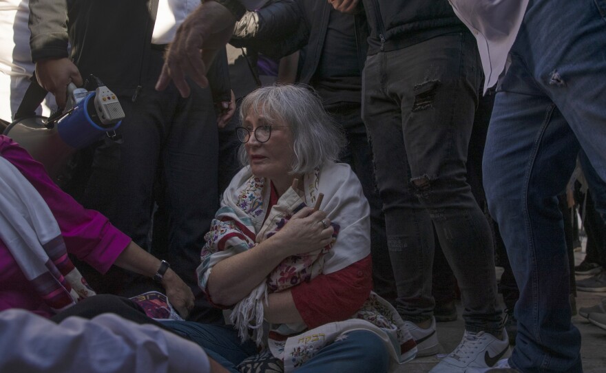 A member of the Women of the Wall clutches a Torah scroll, as she is surrounded by Israeli security forces holding back protesters at the Western Wall.