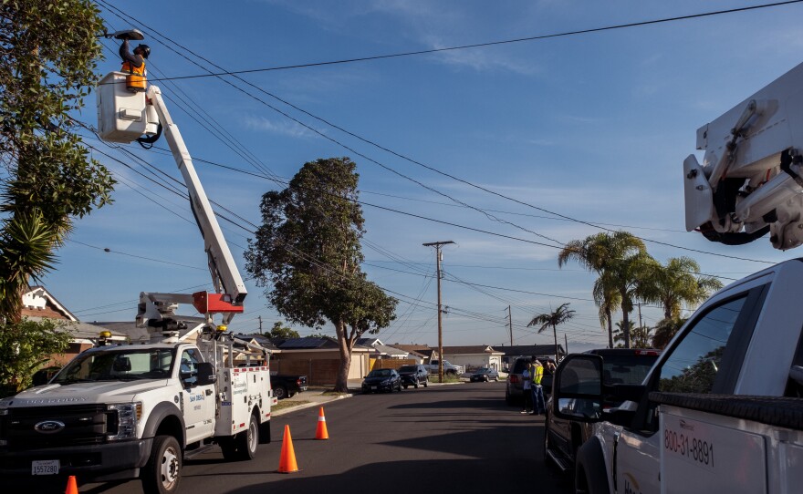 A city electrician replaces a streetlight fixture in San Diego's Bay Terraces neighborhood, March 25, 2022.