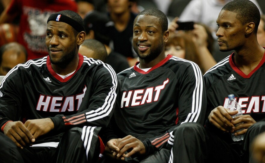 LeBron James (from left), Dwyane Wade and Chris Bosh of the Miami Heat sit on the bench during a game against the San Antonio Spurs. When James and Bosh joined the Heat this year, the team became a juggernaut of talent.