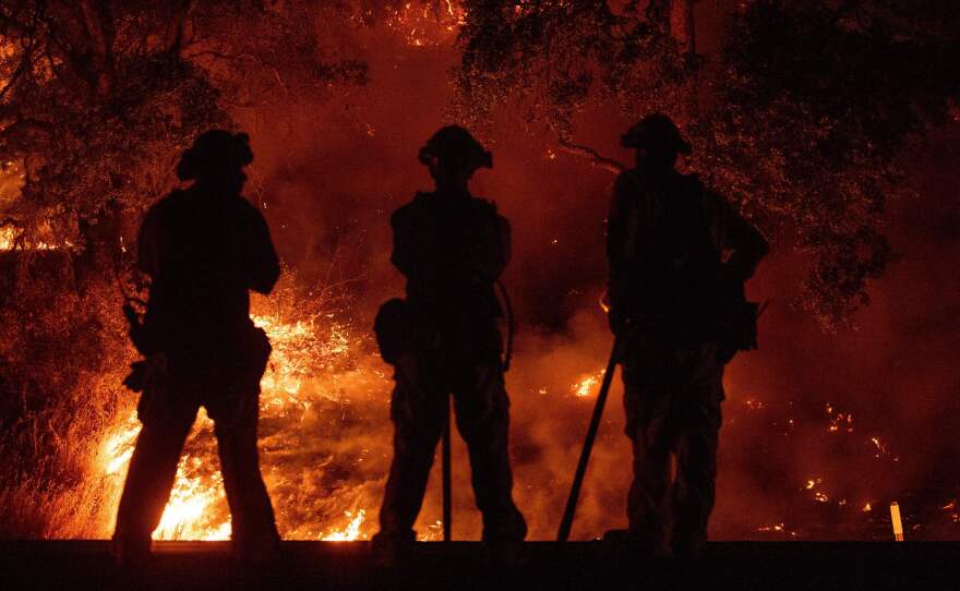 Firefighters keep watch on an area of the Mendocino Complex Fire in Upper Lake, Calif.