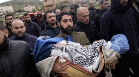 A Palestinian man carries Muhammad Bani Odeh, 5, at the funeral of four members of the Odeh family who were killed in their car by Israeli security forces during an army operation in Tammun, West Bank, Sunday, March 15, 2026.