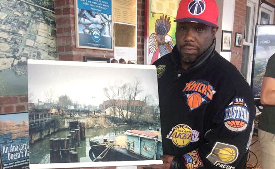 Anthony Satterthwaite, one of the original Earth Conservation Corps members, holds up a photograph of what part of the Anacostia River looked like in 1992.