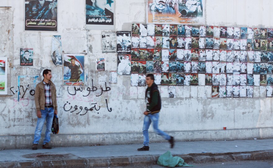 A wall in Tartus is covered in posters commemorating the lives of men who died fighting on Assad's side. Graffiti on the wall says, "Tartus doesn't die."
