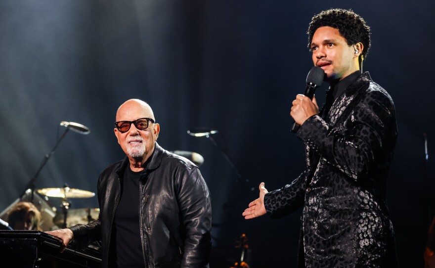 Billy Joel and Trevor Noah speak onstage during the 66th Grammy Awards.