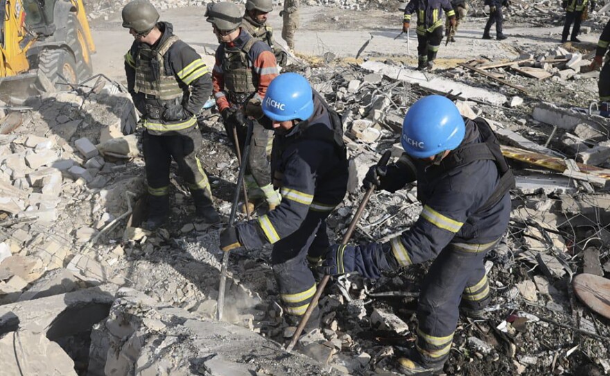 In this photo provided by the Ukrainian Presidential Press Office, emergency workers search the victims of the deadly Russian rocket attack that killed dozens of people in the village of Hroza near Kharkiv, Ukraine, Thursday, Oct. 5, 2023.