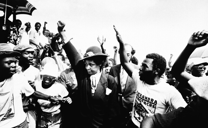 Winnie Mandela raises her fist during the funeral for 17 people who were killed during fierce rioting on Wed. March 5, 1986 in Johannesburg's Alexandra township.