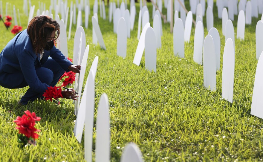 Mary Estime-Irvin, a councilwoman for the city of North Miami, writes the name of a friend lost to COVID-19 on a symbolic tombstone that is part of a pandemic memorial at Griffing Park in North Miami on Oct. 28, 2020.