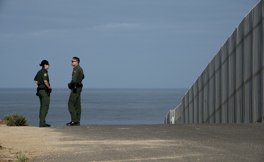 Border Patrol agents Eduardo Olmos, right, and Tekae Michael walk along the frontage road next to primary fencing along the U.S.-Mexico border in San Diego on Aug. 16, 2017. The section of fencing shown here is considered secondary and leads down to the Pacific Ocean. 