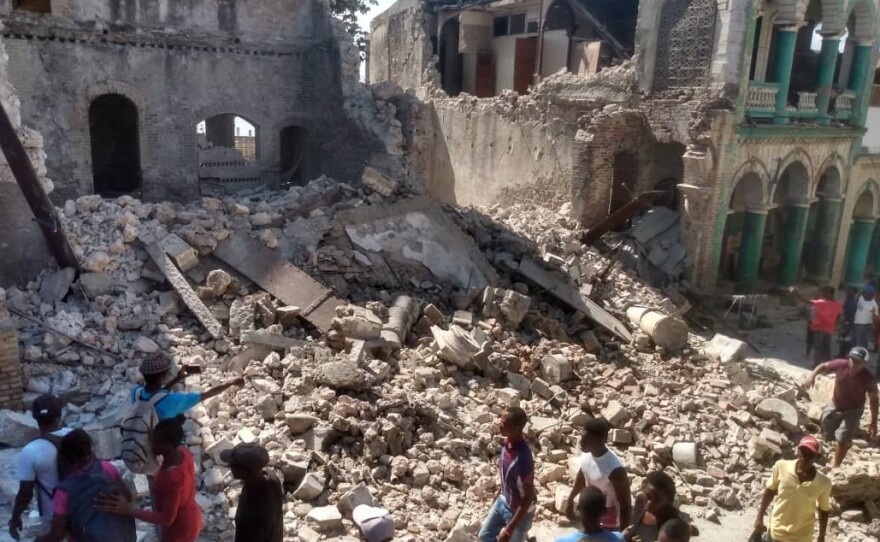 <strong>Sat., Aug. 14:</strong> People inspect damaged buildings.