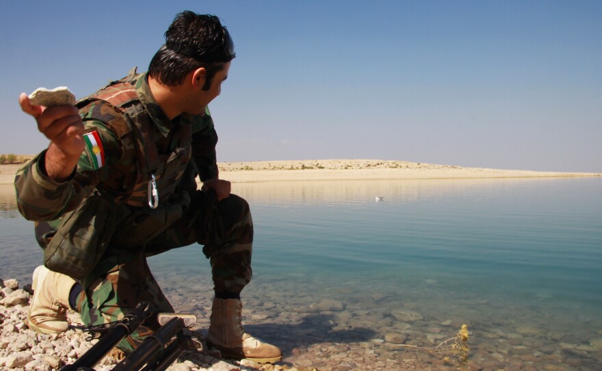 A Kurdish peshmerga soldier skims a stone across the Mosul dam lake on the Tigris river in northern Iraq. The rivers there — the Tigris and the Euphrates — are a source of pride for Iraqis, who in Arabic refer to their country as the land of two rivers.