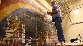Conservator Gary Hulbert layers the mural with resin, tissue paper and fabric before he removes it from the wall. 