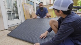 Bhavin Misra and his son, Rumi, attach a solar panel while assembling a plug-in solar kit at their home in Houston.