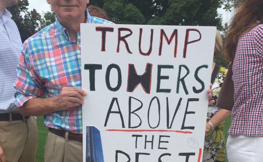 Tom Vales of Greenville, S.C., waits in line outside a Trump speech on Thursday, holding up a homemade sign he made boasting of the GOP frontrunner's business acumen.