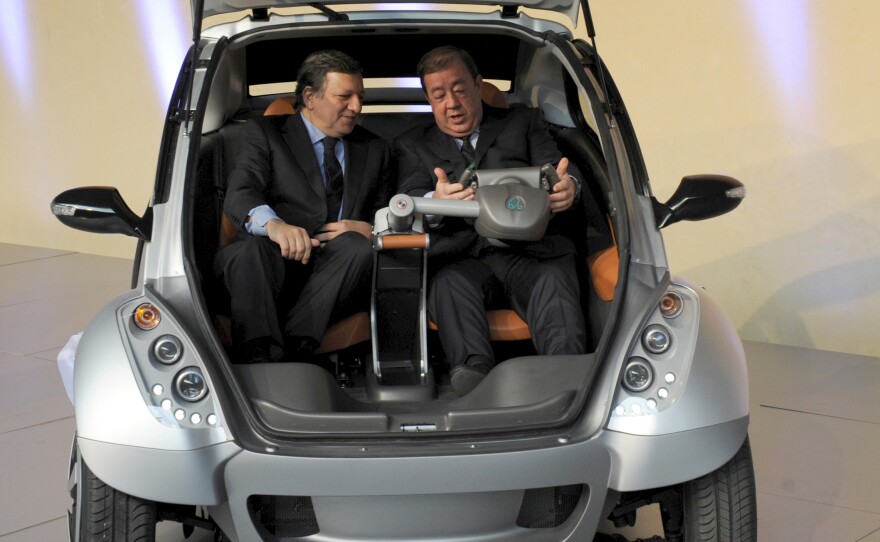 The then-president of the European Commission, Jose Manuel Barroso (left), and Jesus Echave, the Spanish chairman of a consortium of seven small Basque companies, sit together in a prototype of the Hiriko car, during a 2012 event in Brussels.