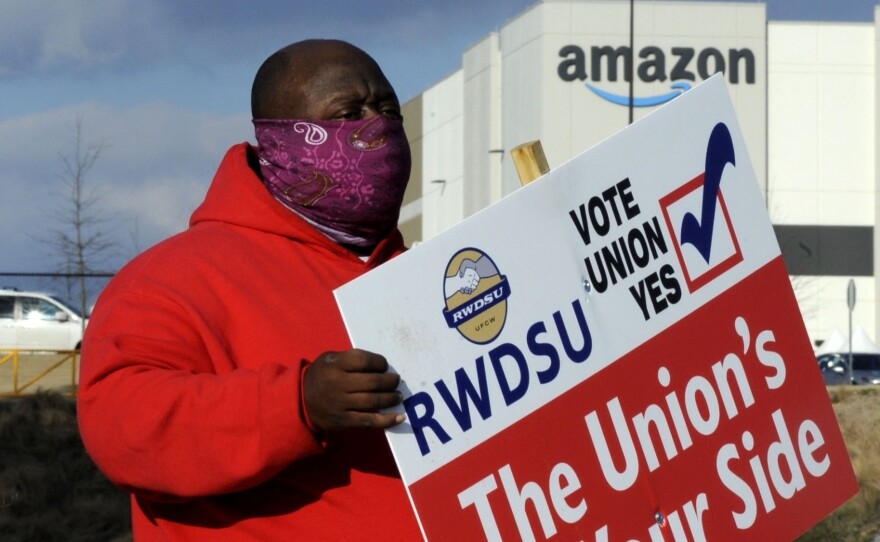 Michael Foster of the Retail, Wholesale and Department Store Union holds a sign outside an Amazon warehouse where workers are voting on whether to unionize.
