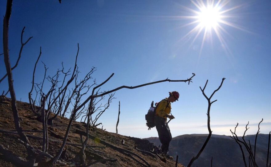 Santa Barbara County Fire Capt. Ryan Thomas hikes down steep terrain rendered barren by the Thomas Fire last month. Authorities announced Friday they had reached 100 percent containment of the fire, which is the largest in modern California history.