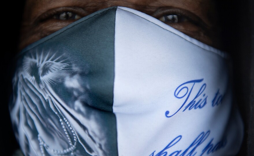 Pedro Rivera waits with other volunteers in District Heights, Md. to hand out food. He's wearing a mask that reads, "This too shall pass."