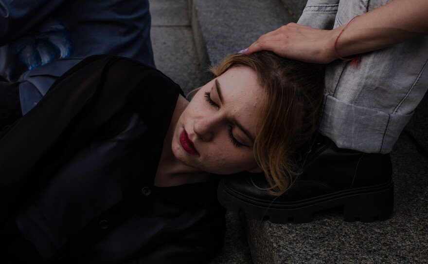 A Phantom Blue dancer rests her head on a friend’s foot on the steps of Maidan Square between recordings.