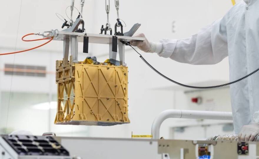 Technicians at NASA's Jet Propulsion Laboratory lower the Mars Oxygen In-Situ Resource Utilization Experiment (MOXIE) instrument into the belly of the Perseverance rover. NASA announced that the instrument had produced oxygen from the Martian atmosphere.