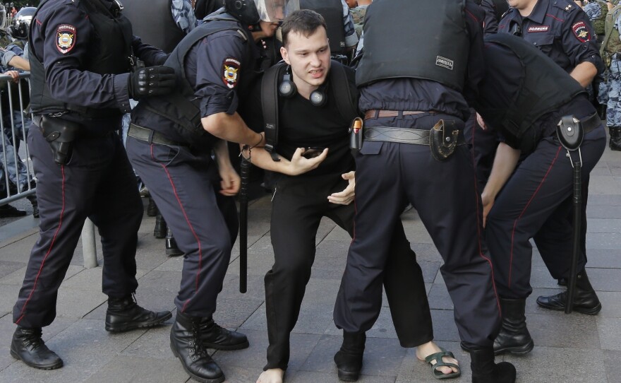 Police officers detain a man at protests in Moscow. Hundreds have been arrested during a demonstration demanding that opposition candidates be allowed to run for the Moscow city council.