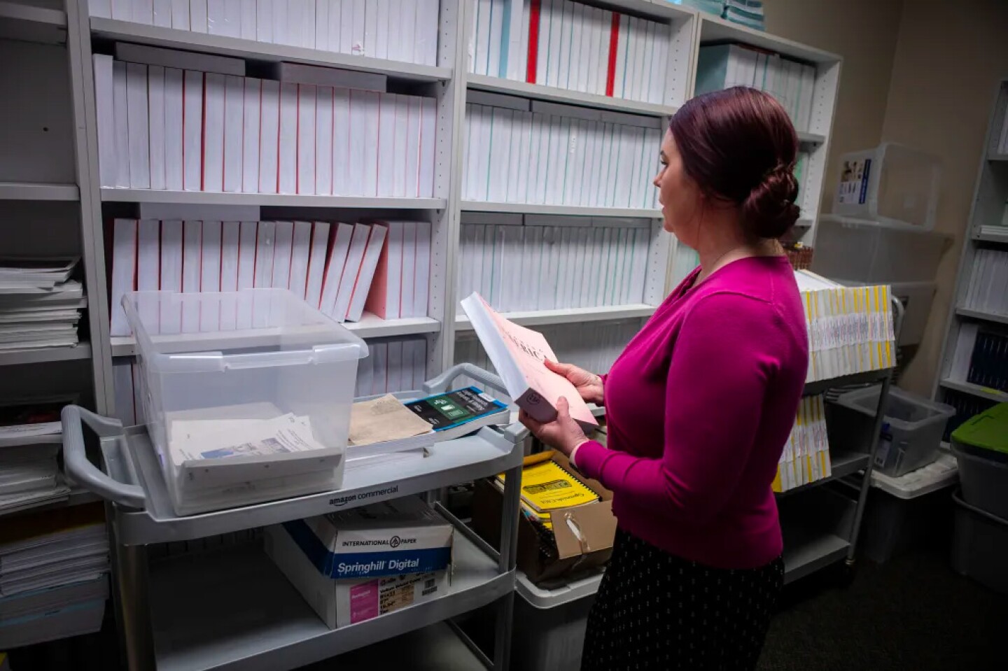 Anna Carlson, the program director for the incarcerated education program, looks over books meant for inmates at Cerro Coso office in Tehachapi on May 10, 2023