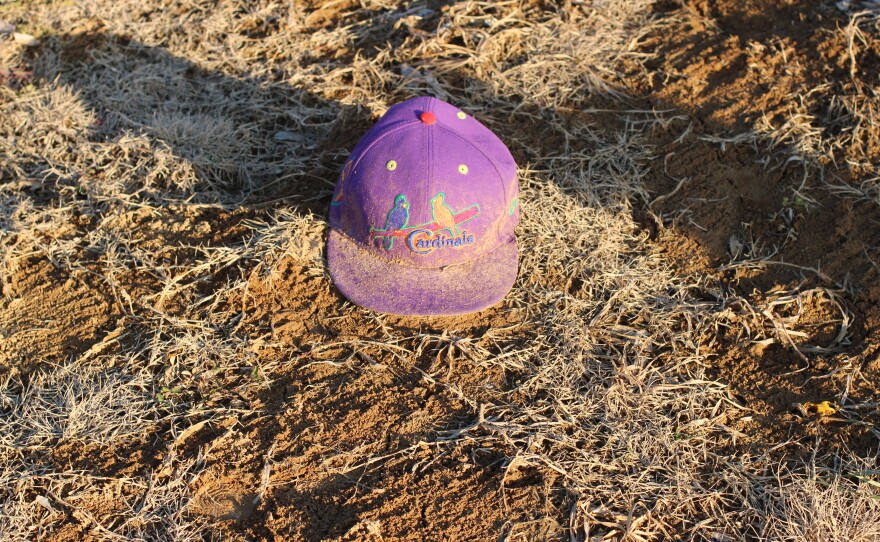 A St. Louis Cardinals baseball cap sits near a grave at Sunset Gardens of Memory in Millstadt, Illinois. In this 30-acre cemetery, groundskeepers often see memorabilia, toys, and other keepsakes near gravesites.