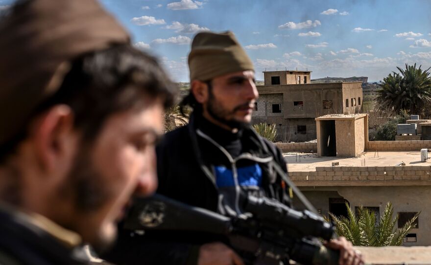 U.S.-backed fighters stand guard on a building during shelling of the Islamic State's last holdout in the town of Baghouz, Syria, on March 3.