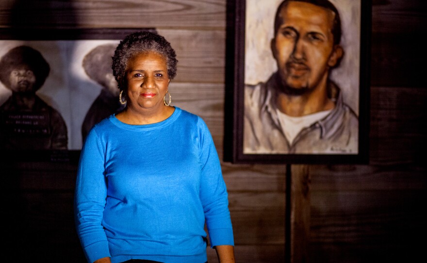 Mac's mother, Sheila Phipps, stands with a portrait she painted of her son, part of a series called Painted Justice, depicting prisoners who were wrongfully or harshly accused.