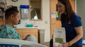 Elsa Morales-Roth (right), executive director of the Emilio Nares Foundation, hands a snack bag to a child recovering from chemoin this undated photo. 