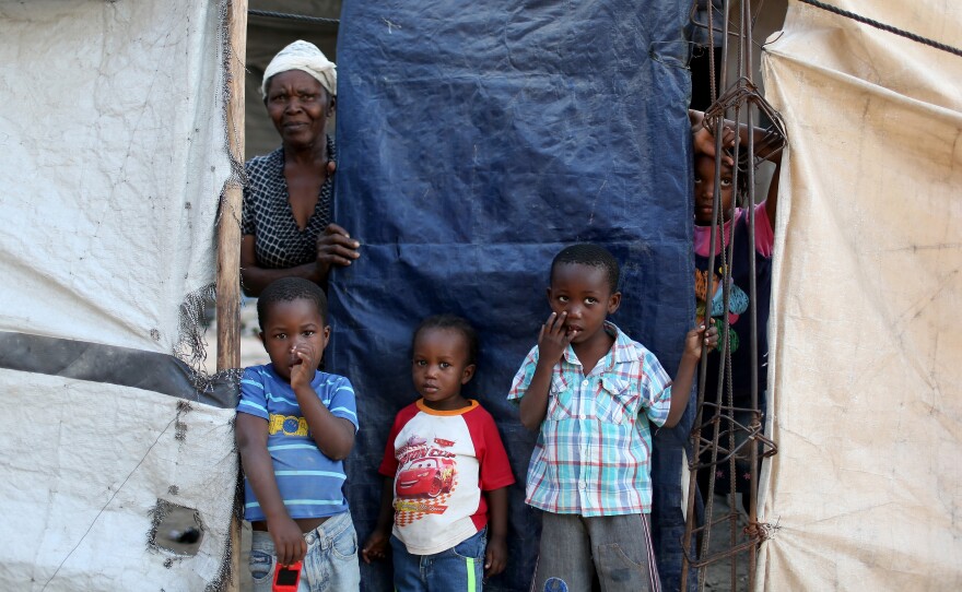 A family looks out from behind the tarp that serves as the front door to their home. The structure was built five years ago over the land where their home stood before the 2010 earthquake. At one point, about 1.5 million people lived in tents across Haiti. Now about 80,000 people live in these structures.