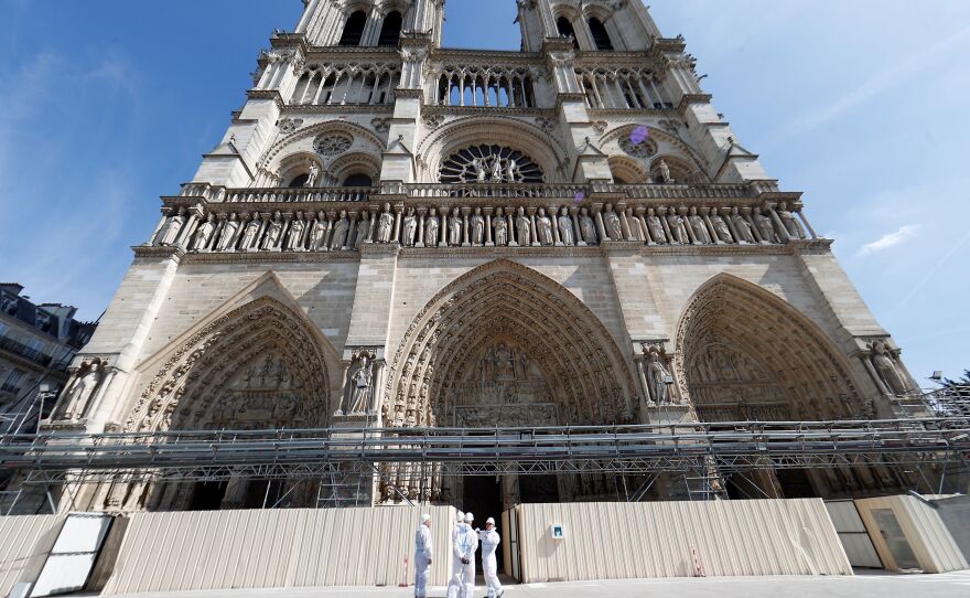 Workers stand outside the reconstruction site at the Notre Dame Cathedral in Paris on Friday.