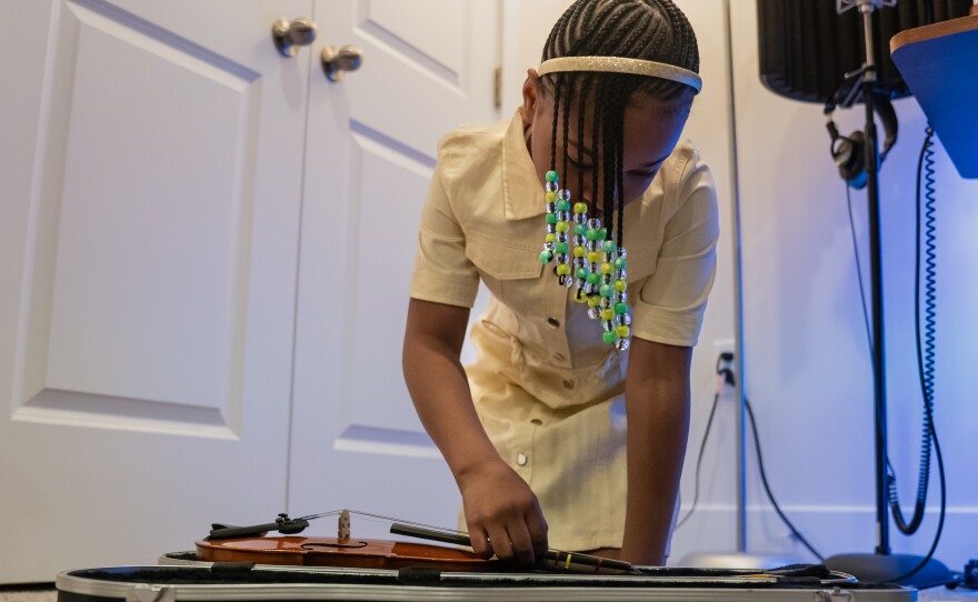 Aura takes out her violin to practice before school.
