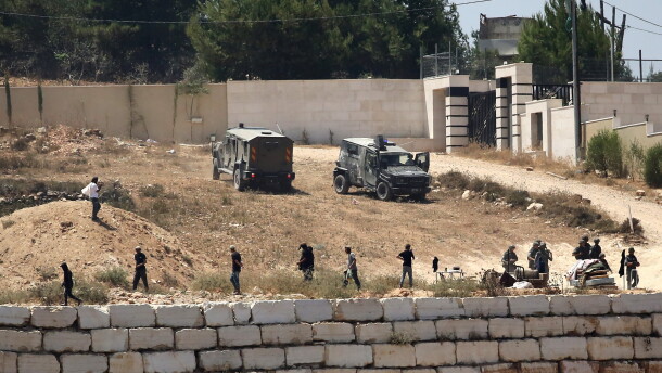 Israeli soldiers stand guard next to settlers in front of Palestinian homes that they have blockaded in the village of Qusra, south of Nablus, in the occupied West Bank, Wednesday, Aug. 12, 2026.