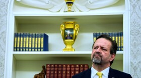 Sebastian Gorka listens as President Donald Trump speaks with reporters after signing executive orders in the Oval Office of the White House, April 23, 2025, in Washington.