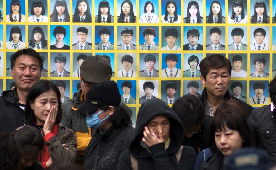 Relatives of victims of the Sewol ferry accident stand before a banner featuring victim photos during a protest. More than 300 people, most of them high school students, died in the accident. Nine people remain missing.
