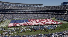 Military personnel haul a giant flag onto he field before the Charges play the Detroit Lions in an NFL football game Sunday, Sept. 13, 2015, in San Diego. 
