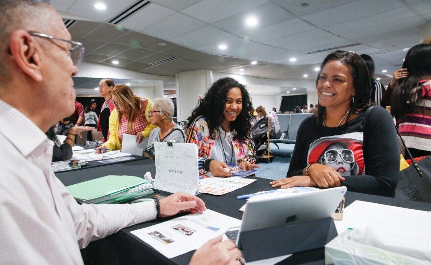 Conchita Santiago, a principal in Puerto Rico, speaks with Javier Melendez, director of human resources at Orange County Public Schools, at the welcome center for Puerto Ricans at the Orlando airport.