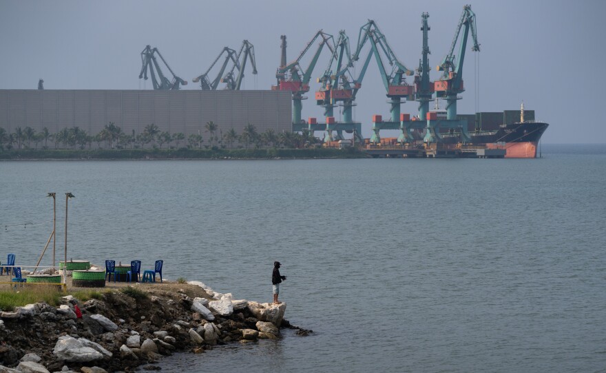 A man fishes next to shipping equipment  in Indonesia's Morowali Industrial Park in December 2025.