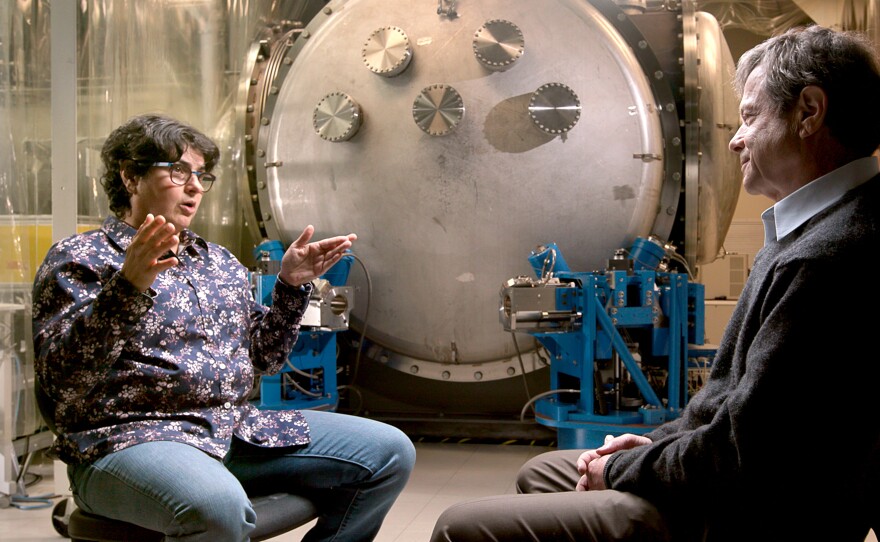 In a working MIT high bay, in front of a prototype vibration cancelling instrument, MIT’s first female Dean of Science explains LIGO to Alan.