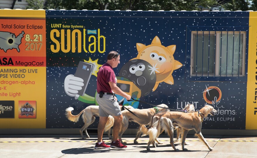 Jim Blair walks Saluki dogs past a solar eclipse exhibit on the campus of Southern Illinois University in Carbondale, Ill. With approximately 2 minutes 40 seconds of totality the area in Southern Illinois will experience the longest duration of totality during the eclipse on August 21.
