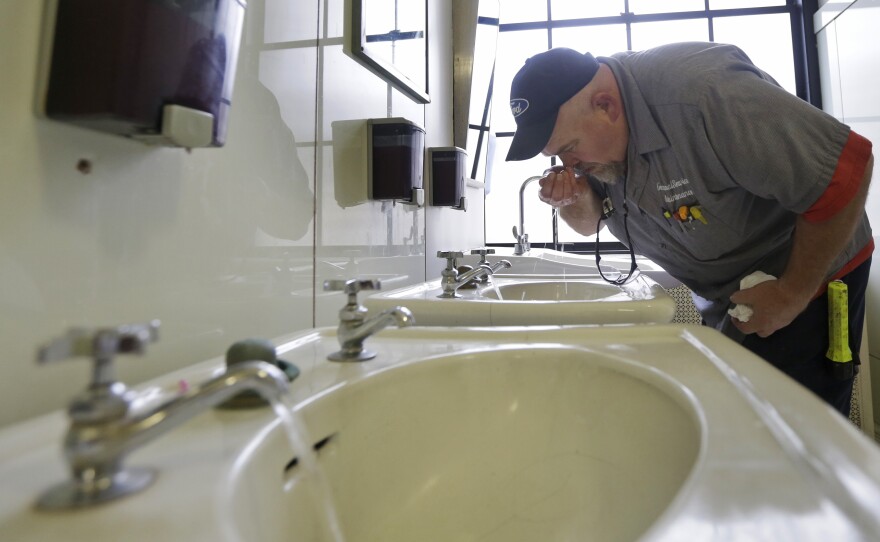 In West Virginia, a ban on water use has been lifted in at least three areas affected by a chemical spill. Here, Al Jones of the state's General Services department tests the water as he flushes a faucet and opens a restroom on the first floor of the Capitol in Charleston on Monday.