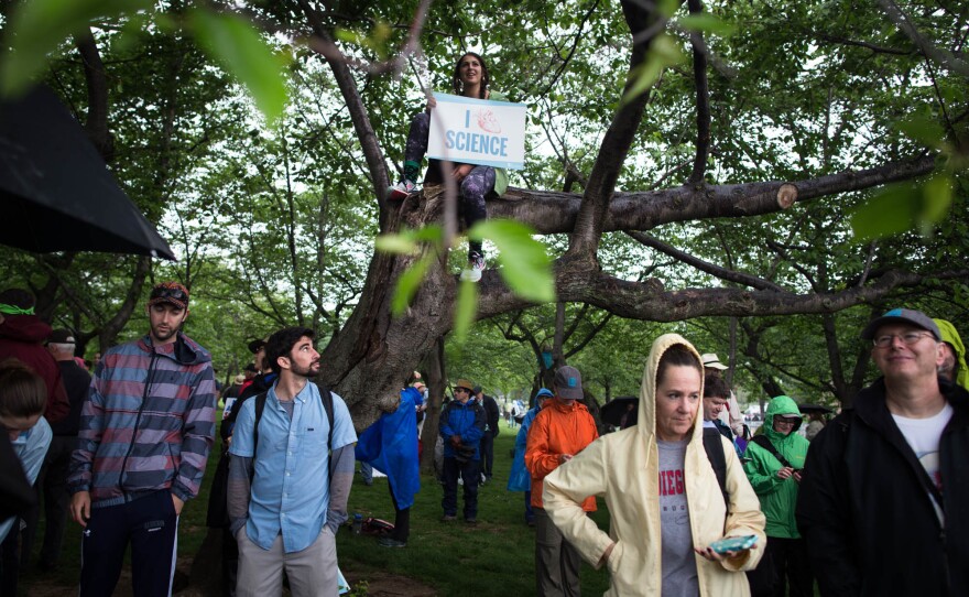 Participants seek cover from the rain to watch the rally.