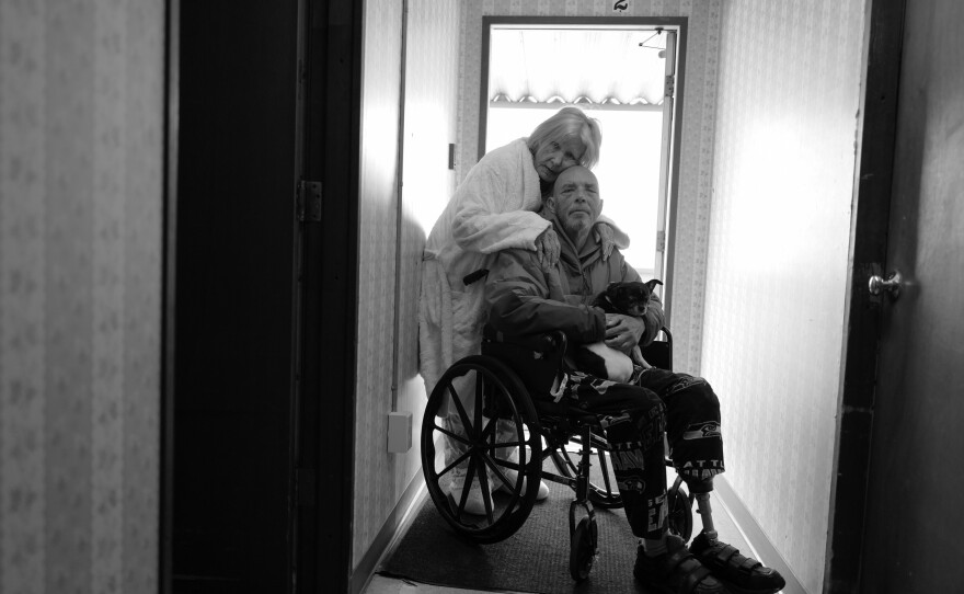 Karen hugs Tony in his wheelchair on April 14, 2022. They now live in Burlington, Wash., and their mobile home no longer exists on the island. They are grateful to be together after being separated for long periods of time during the pandemic.