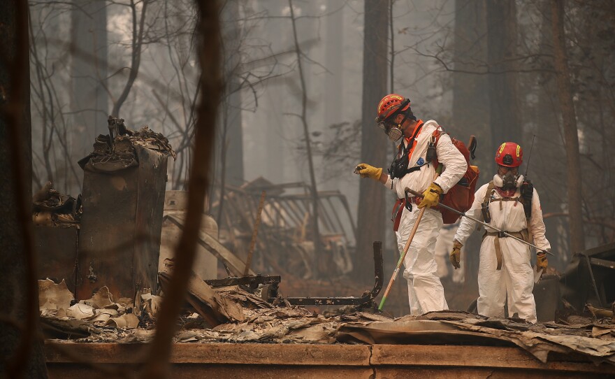 Rescue workers search for human remains on Thursday at a home that was burned by the Camp Fire in Paradise, Calif.