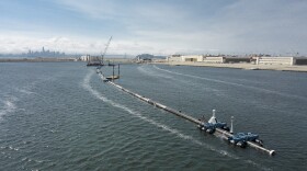 In this Monday, Aug. 27, 2018 photo provided by The Ocean Cleanup, a long floating boom that will be used to corral plastic litter in the Pacific Ocean is assembled in Alameda, Calif.