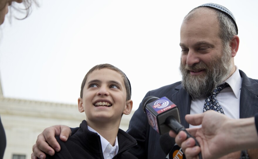 Menachem Zivotofsky and his father, Ari Zivotofsky, gather to speak to media outside the Supreme Court in Washington on Monday. The court is taking its second look at a dispute over the wording of U.S. passports for Americans born in Jerusalem, a case with potential foreign policy implications.