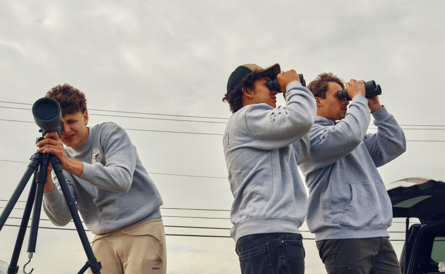 Train (left), Pacetti and Trojan look through a scope and binoculars at Malibu Beach Wildlife Management Area.