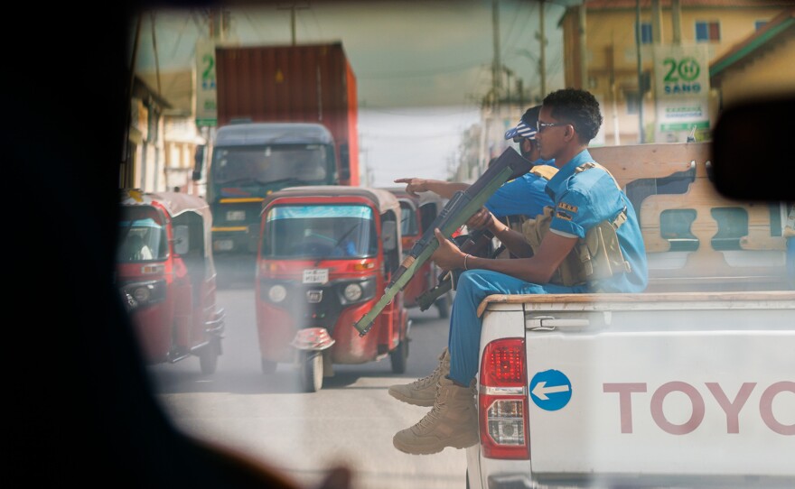 A private security team escorts an unmarked U.N. vehicle through the streets of Mogadishu. Aid workers, private business people, government officials and Western journalists regularly use bulletproof cars flanked by armed security details to move through the capital.