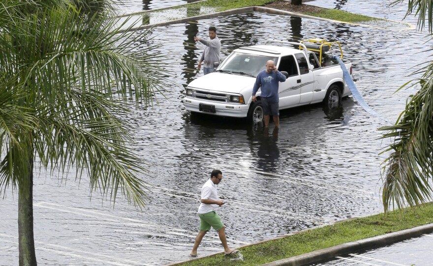 Workers pump water from the parking lot of the Dadeland Plaza shopping center on Thursday after heavy rains triggered by T.S. Karen in Pinecrest, Fla., a suburb of Miami.