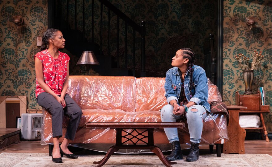 In "Mud Row," two sisters are seated on a couch wrapped in plastic.
